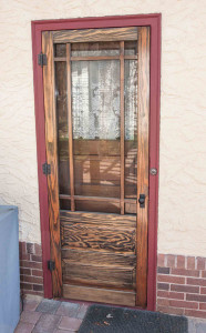 photo of stained wood storm door with reddish door trim.