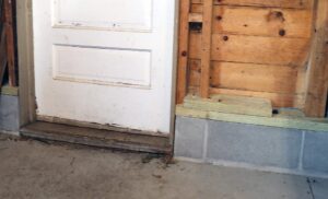 Bottom of white door beside foundation blocks.