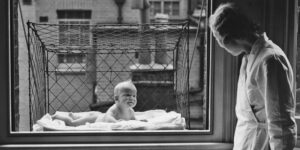 Baby in window cage and woman.