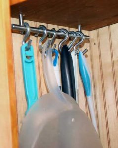 Metal rods on either side of the lower cabinet space feature S-hooks to hang a variety of taller items. 