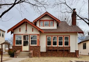 A tan stucco and brick bungalow.